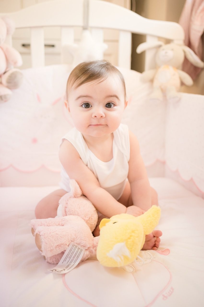 Preparativi battesimo Roma — bambina seduta nel lettino con peluche, prima della cerimonia